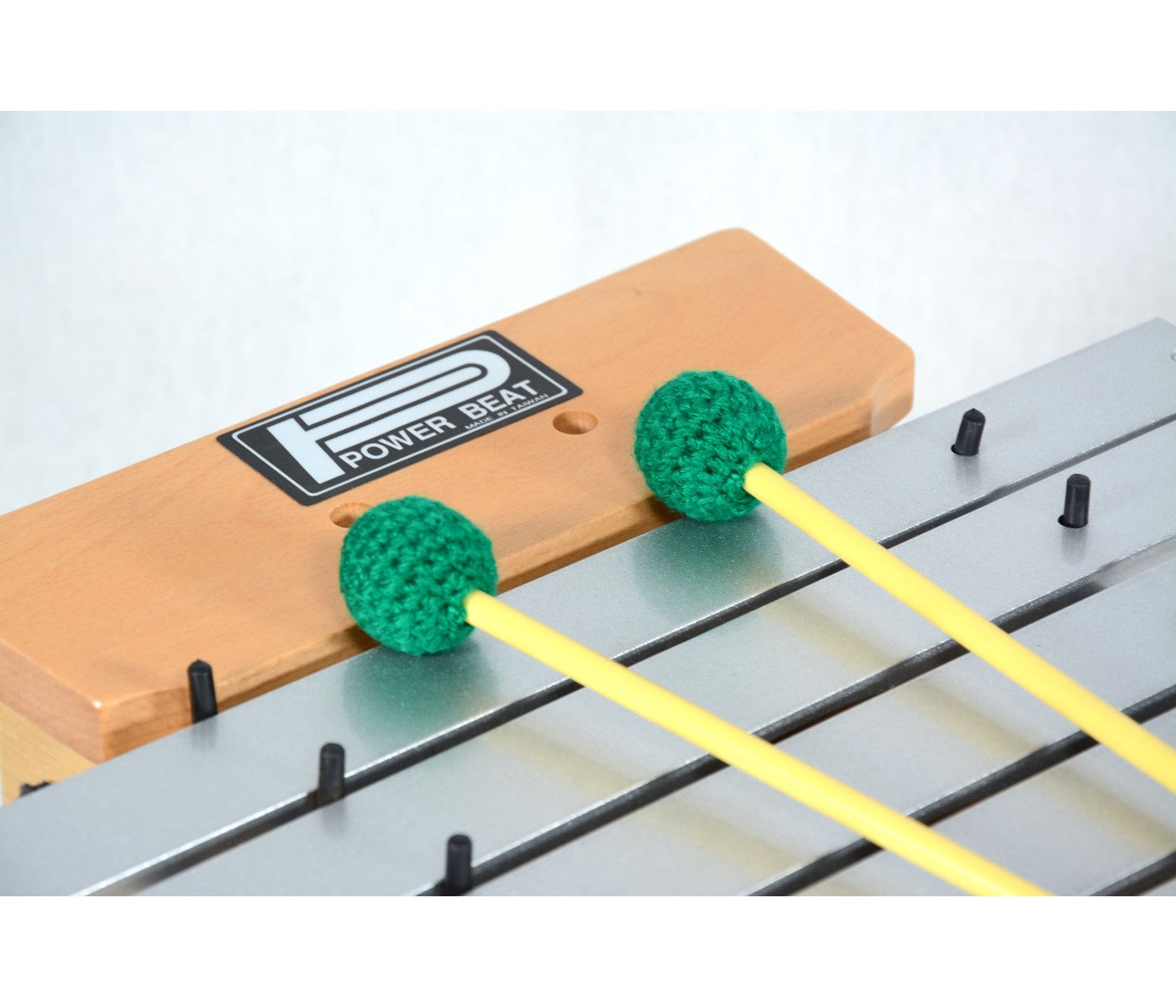 Wooden drumming practice pad with green foam drumsticks on a white background
