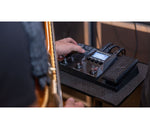 Guitar effects pedal being used with a guitar, blurred background