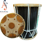 A traditional Arabic drum with a black body and a skin-covered surface, alongside its cover which has circular cut-outs arranged in a pattern.