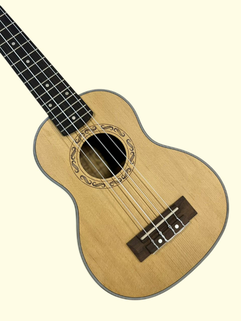 Nylon-string ukulele with decorative inlay on a beige background