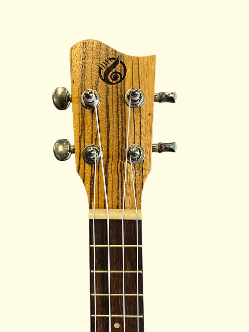 Close-up of a wooden ukulele headstock with tuning pegs on a white background