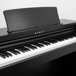 Kawai CX202 Satin Black digital piano close-up showing the Kawai logo, music rest, black and white keys, and front control area