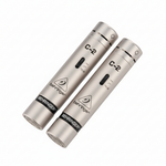 Two Behringer C-2 silver matched condenser microphones shown in a diagonal three-quarter view with cylindrical bodies, grilles, C-2 markings, and Behringer logos