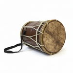 Large Rahmani hand drum lying down at an angle with its natural drumhead, brown body, light rims, rope tensioning, and shoulder strap visible on a white background