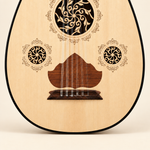 Close-up of the oud lower soundboard showing bridge, strings, brown pickguard and floral rosettes