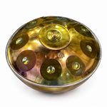 Egyptian-inspired metal handpan drum at an angled view showing the rounded shell, central dome, and tone fields