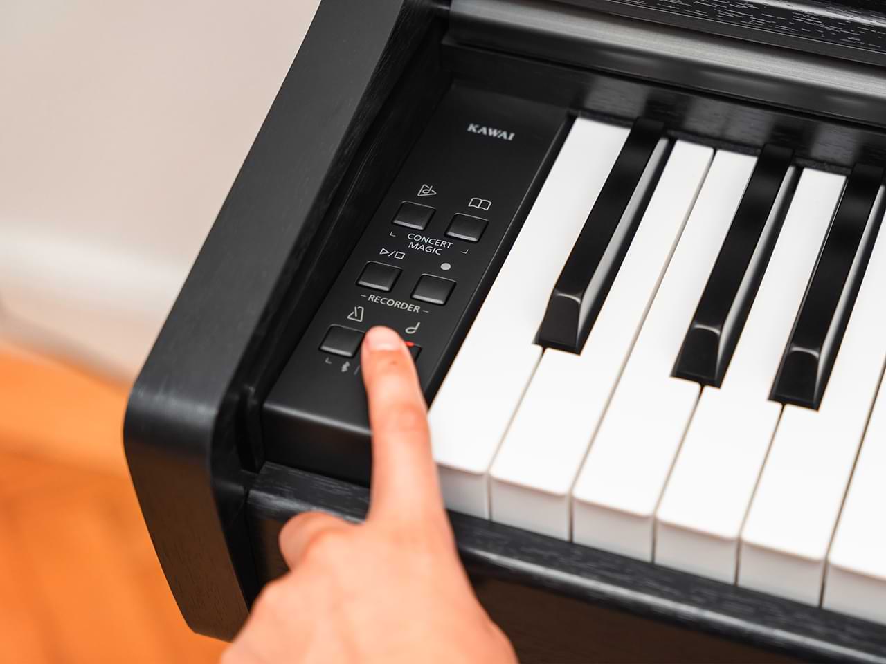 Digital piano with a hand pressing a button on the control panel