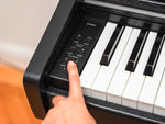 Digital piano with a hand pressing a button on the control panel